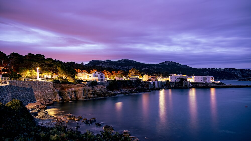 Häuser in Sant Elm, Mallorca, in der Dämmerung am Meer.