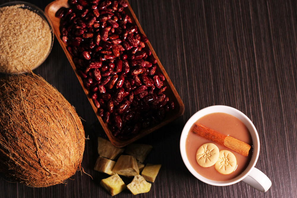 Dominikanisches Habichuelas con dulce neben roten Bohnen und einer großen Kokosnuss.