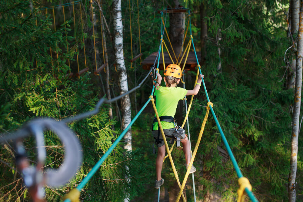 Costa Rica Family Hotels: A young boy climbing on the high ropes of a tropical forest