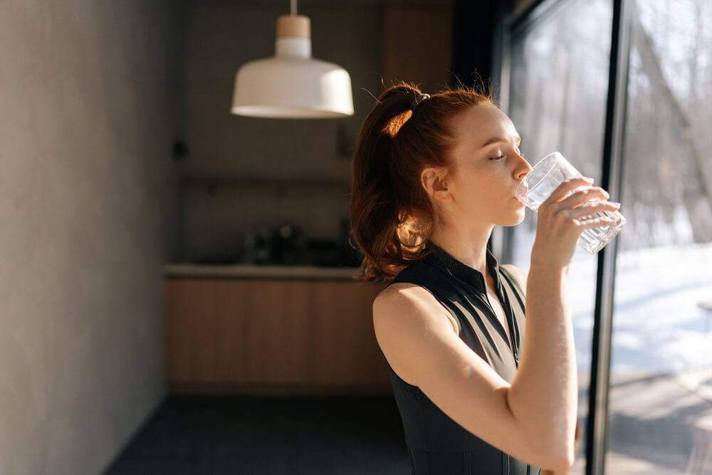 A woman drinking water to stay healthy on a fitness vacation 