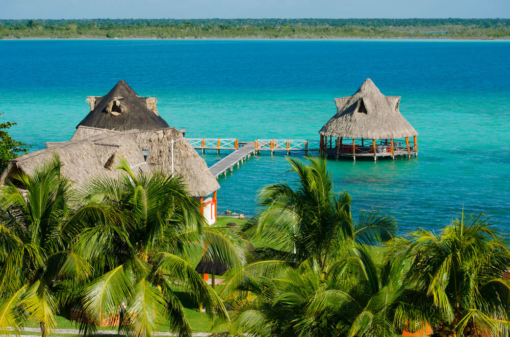 Mexiko schönste Orte: strohbedeckte Häuser auf dem Wasser in Bacalar.