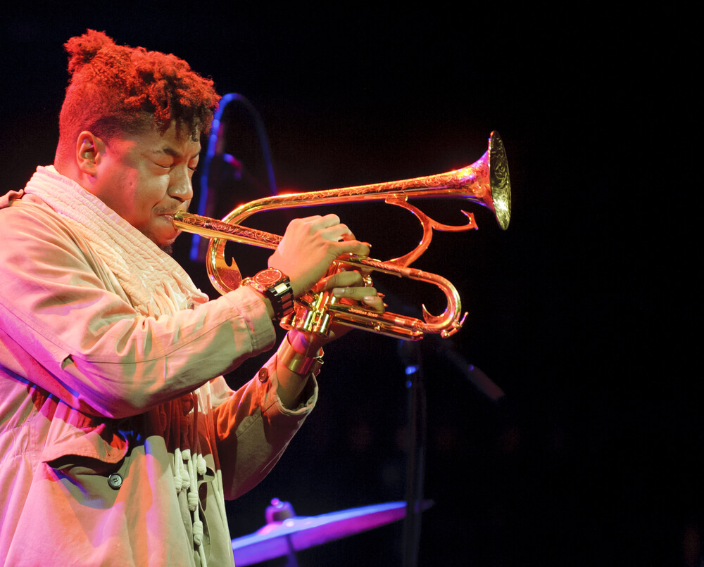 Music Festivals in Europe: Black man dressed in beige playing the horn