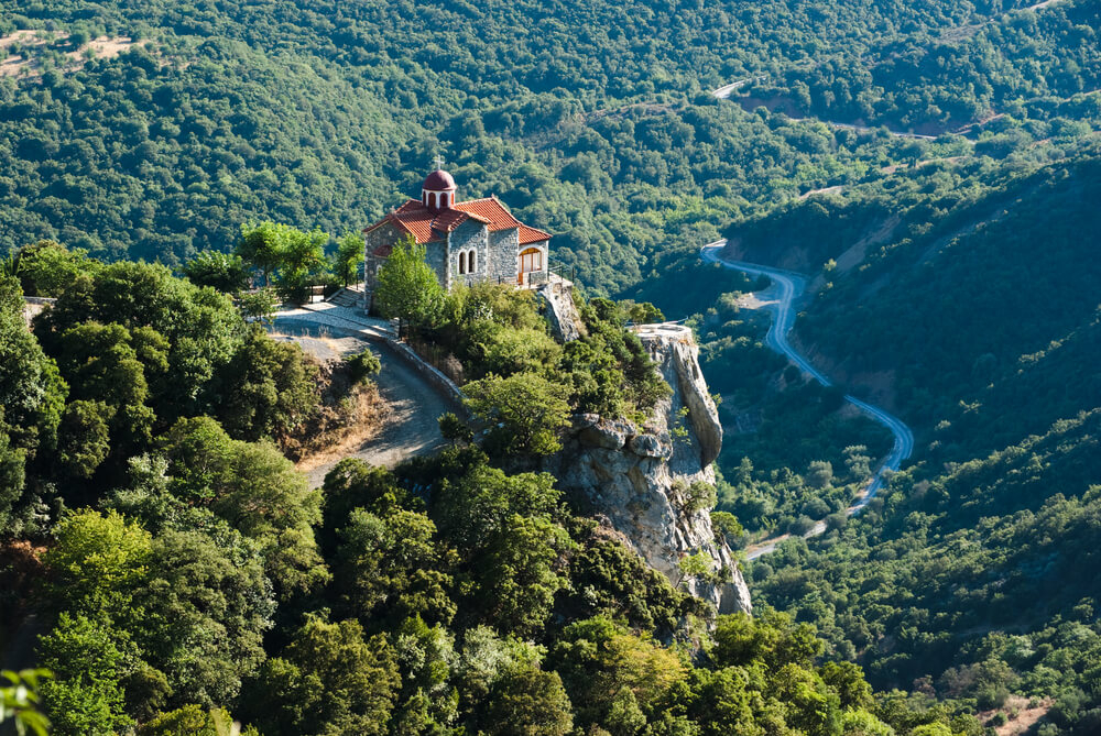 Arcadia: Green, lush mountains of the Lousios Gorge with a house in the middle 