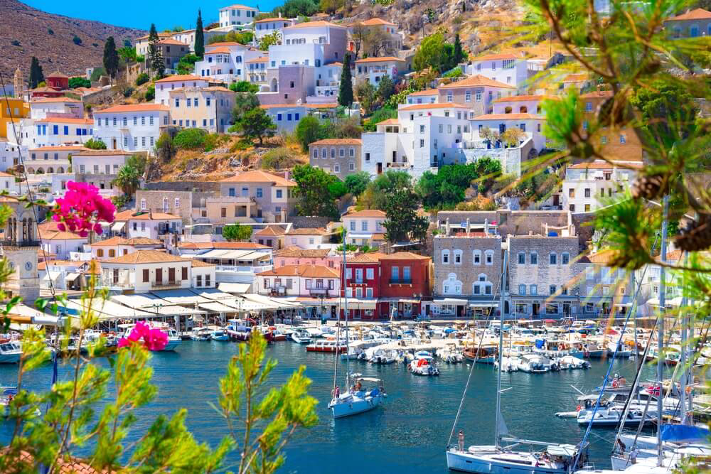 Hydra: A view of the town from the harbour with houses on a hill and boats on the water