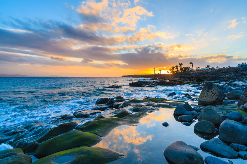 Sonnenuntergang mit dem Faro de Pechiguera in Lanzarote am Horizont.