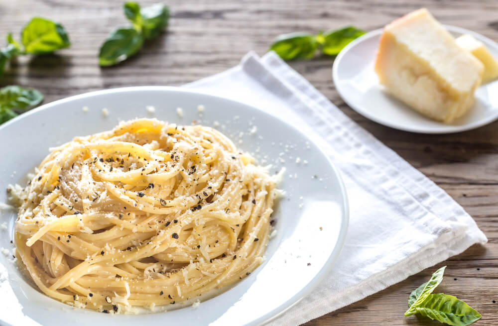 Cacio e Pepe: A white bowl full of spaghetti in a creamy cheese sauce