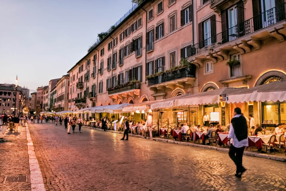 Roman cuisine: A cobbled street of Navona Square lined with restaurants at night