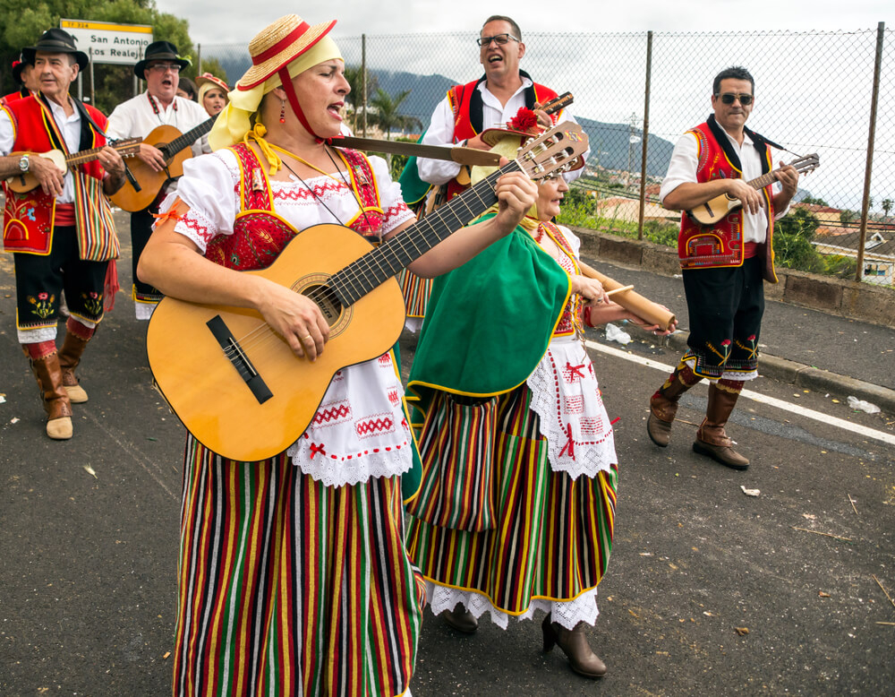 Romerías Tenerife: a group of people in traditional dress parading in the street