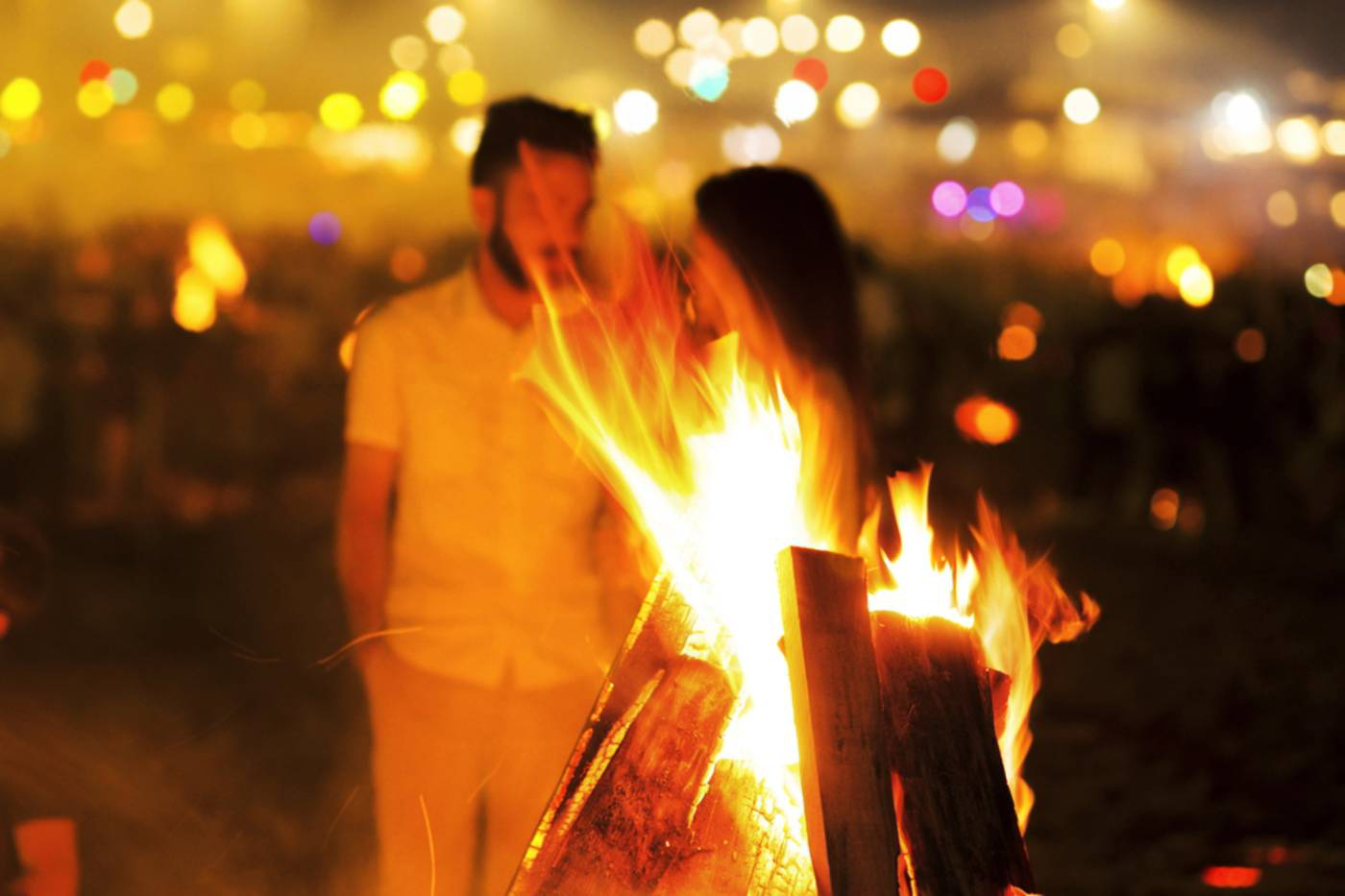 San Juan Festival: Bonfire on the beach with a couple chatting nearby