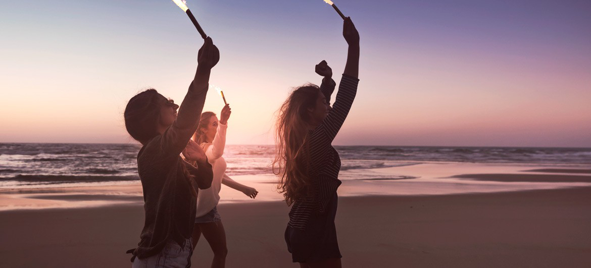 Silvester in der Sonne: junge Menschen mit Fackeln am Strand