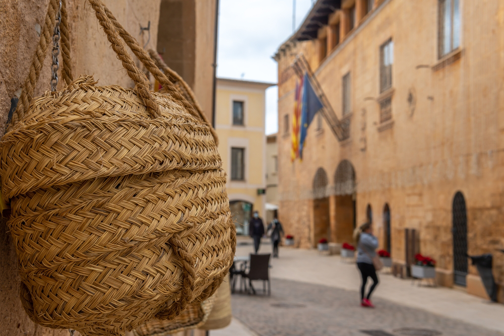 Straße in Mallorca mit Flechttasche im Vordergrund.