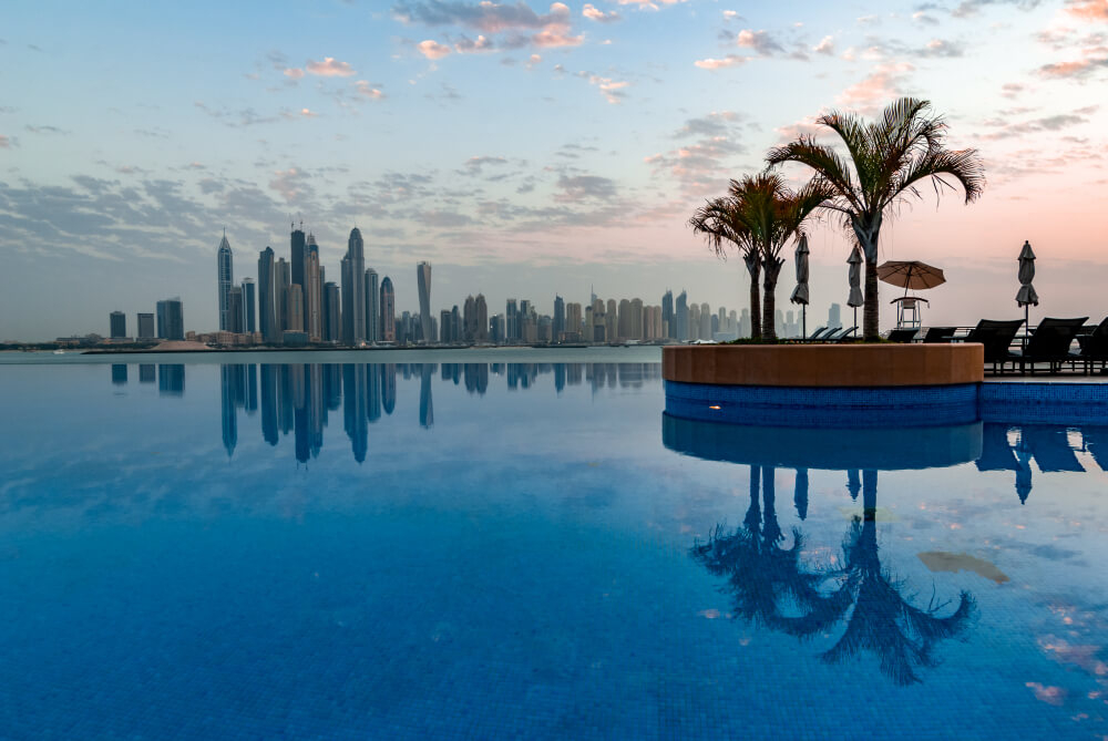 Dukes The Palm: An infinity pool with a small bar in the middle and views of Dubai