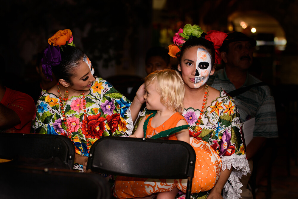 TXT ALT FOTO 6	Día de Muertos: kleines Kind mit verkleideten Frauen im Erlebnispark Xcaret.