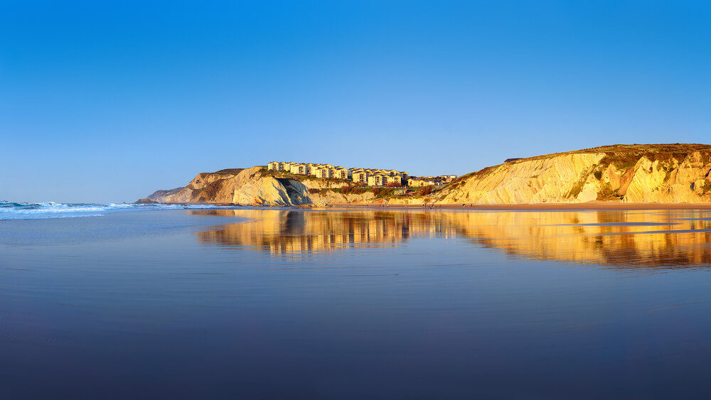 Bilbao beaches: Golden cliffs and vast sandy beach of Atxabirlbil at sunset