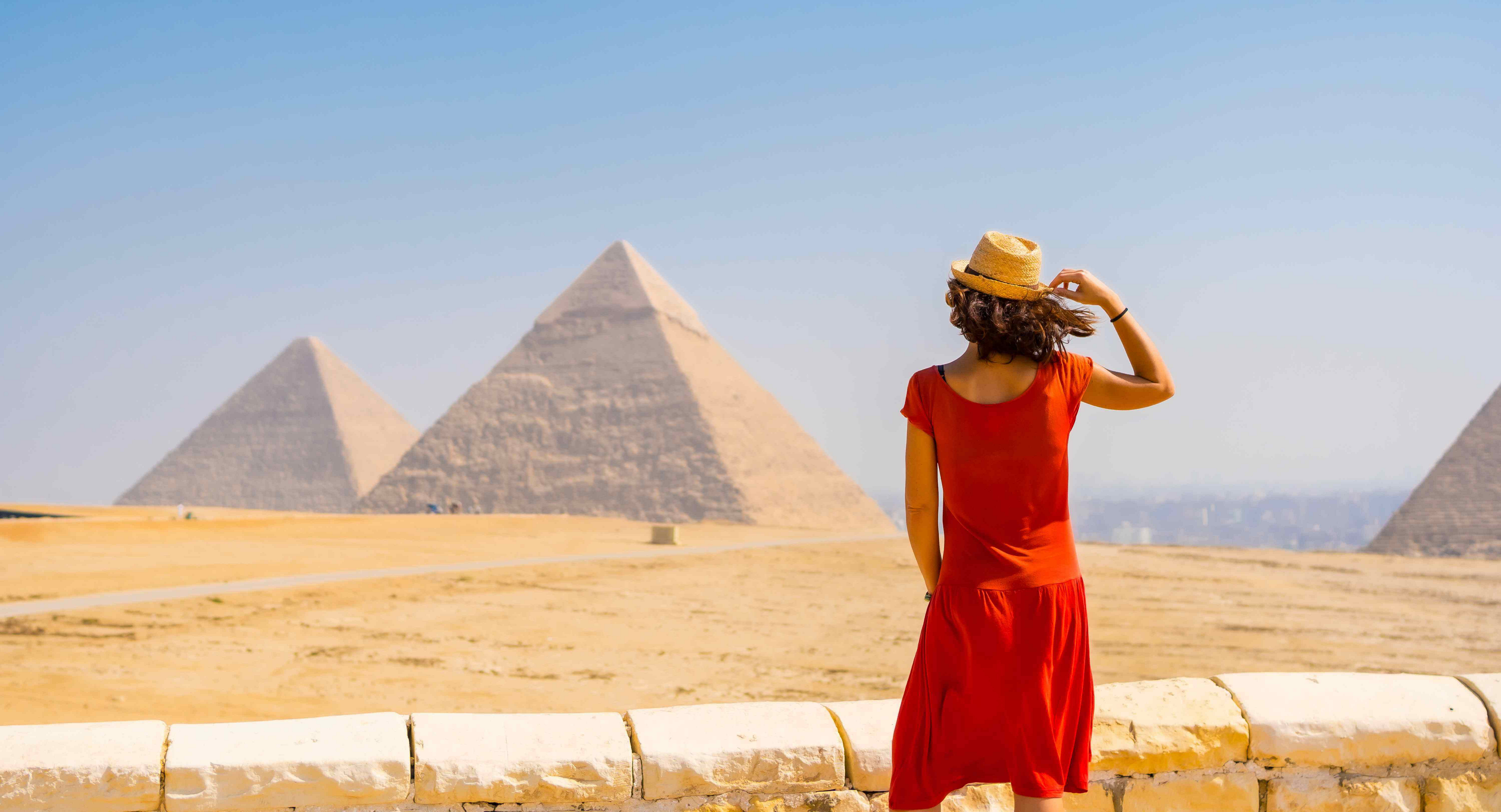 Things to do in Cairo: A woman in a red dress standing, looking out at the pyramids