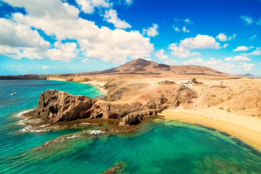 Things to do in Lanzarote: Golden sand beach and mountains with blue sea at Papagayo Beach