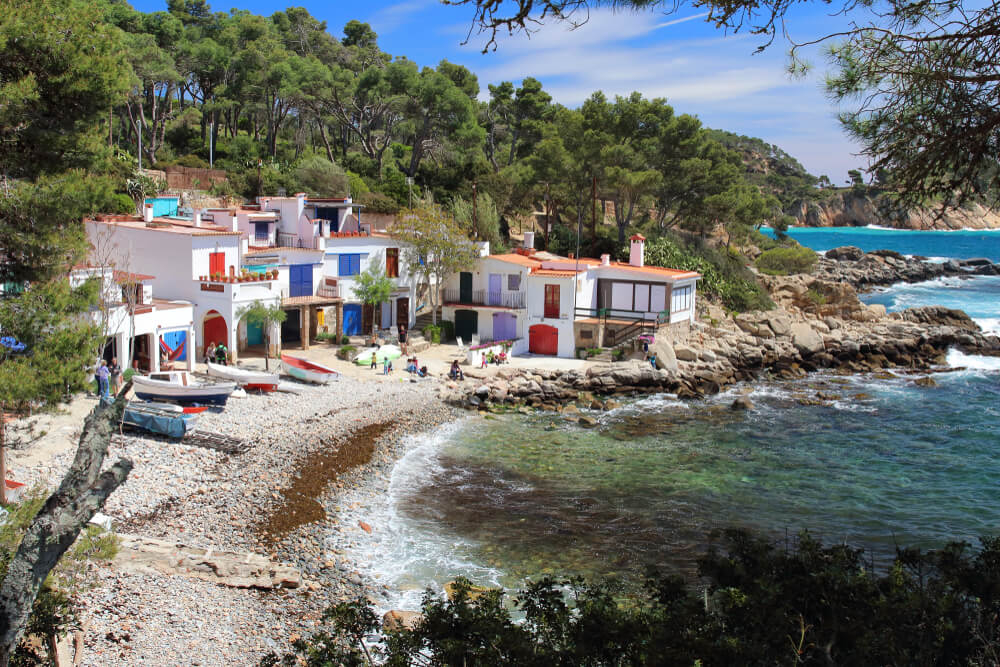Cala S’Alguer: A small bay, blue water, white sand and white buildings with colourful doors