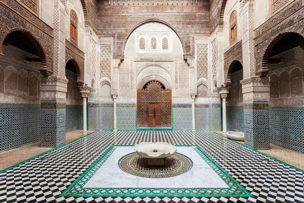 Al-Atterine Madrasa: A white chiselled stone Moroccan building with green mosaic