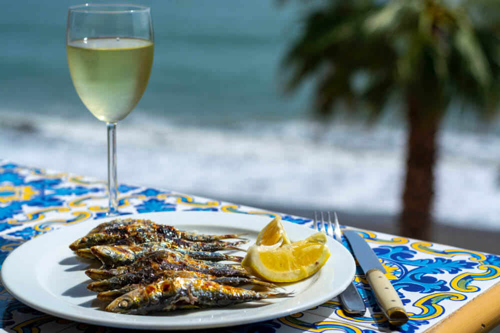 Traditionelle mediterrane Küche: Espetos am Strand mit einem Glas Weißwein.