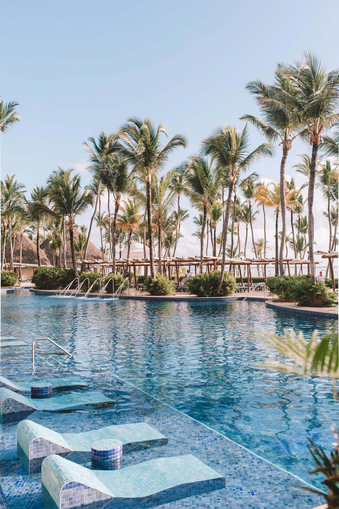 Barceló Bávaro Beach: A row of palm trees next to an outside pool and loungers