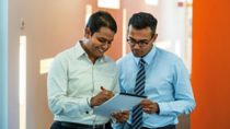 Two men collaborating on a notepad 