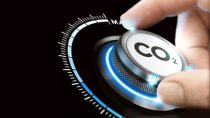 Man turning a carbon dioxide knob to reduce emissions. CO2 reduction or removal concept. Composite image between a hand photography and a 3D background.