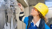 female engineer with yellow hard hat  and protective glasses looking at face covering