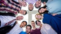 People arranged in a circle smiling and looking down 