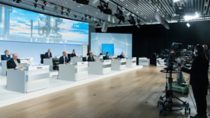 Press conference with BASF employees in suits sitting at tables equally distanced apart