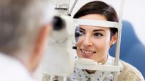 Dark hear woman look in ophthalmoscope to determine diopter in clinic