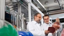 Two scientist wear red safety goggles analyzing chemical holding cue cards 