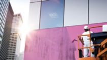 Painter on an industrial lift painting a building pink