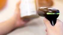 Person holding a black price scanner while scanning an item
