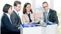 Group of people in suits looking at a laptop