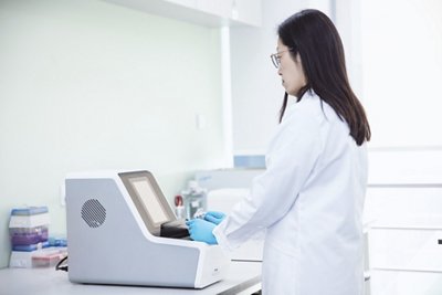 The Accellix platform being worked on by a woman in a lab for automated flow cytometry.