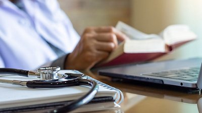 Sepsis Photo of a doctor reading a book in his office with a stethoscope on the desk