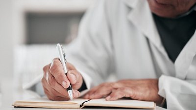 Syndromic testing Photo of a doctor taking notes in a notebook