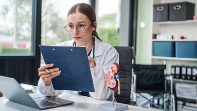  Acute Kidney Injury A female scientist reviewing her notes to transcribe them into her computer