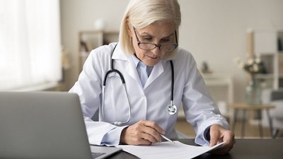  Antimicrobial Resistance & Stewardship Female doctor looking at some documents in her office