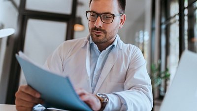 Syndromic testing A doctor wearing glasses in his office, looking at files