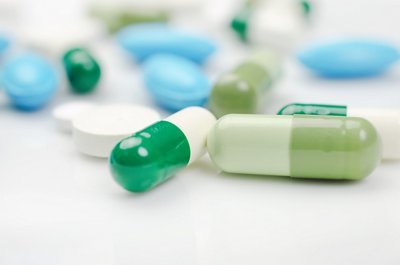 Close-up. Pharmacy theme. Blue and green pills on the white surface
