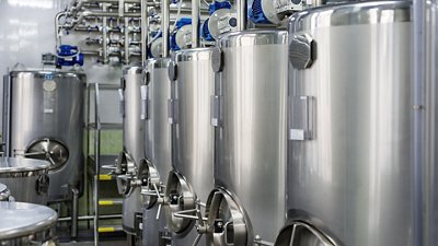 A series of gray metal tanks for mixing liquids.