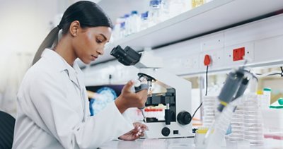 Woman, science and working with microscope in laboratory, microbiology and research study of organisms. Specimen, analysis and bacteria or antimicrobial resistance, medicine and vaccine development.