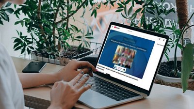Visual of a person viewing a BioMérieux global webinar on a laptop, focused on adult sepsis management. The scene is set in a home workspace with plants, highlighting accessible digital medical education and remote learning.