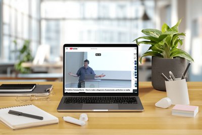 Visual of a laptop showing a BioMérieux webinar focused on pneumonia diagnosis, featuring a clinical presentation by a healthcare expert. The scene is set in a modern workspace with office elements, highlighting digital medical education and professional learning.
