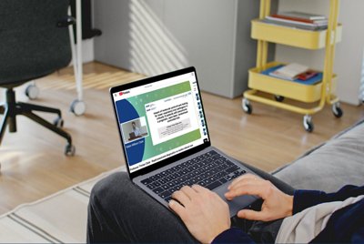 Visual of a person watching a BioMérieux webinar on a laptop featuring Professor Tristan Clark, focused on rapid pneumonia diagnostics compared to routine clinical care. The scene highlights digital medical education in a home environment.