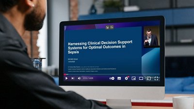 Photo of a man watching Dr. Rawson’s video on Sepsis Management among BSI and Clinical Algorithms Decision Support Systems on a computer.