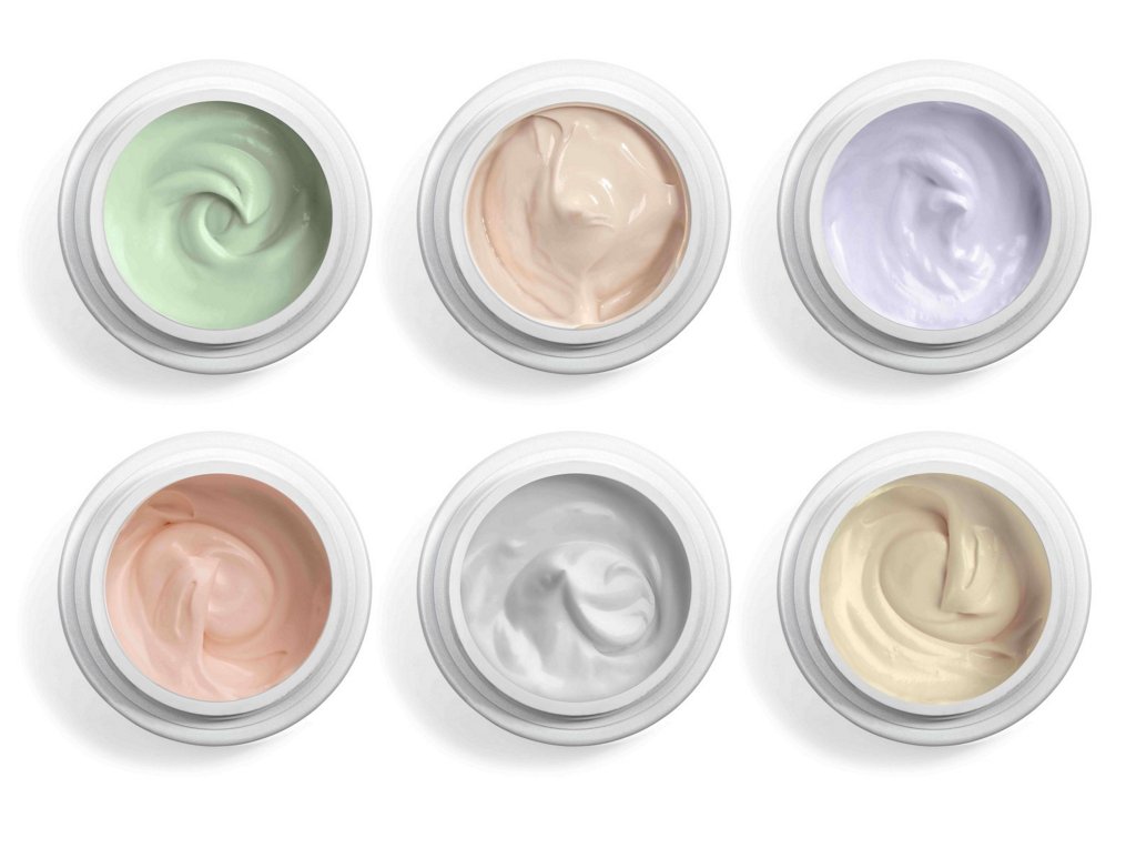 Different colored cosmetic creams on a white background 