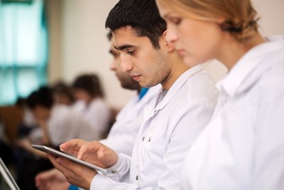 Medical student or young doctor using tablet computer during lecture, conference or symposium