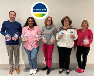 Five bioMérieux employees stand together holding 9 awards. 